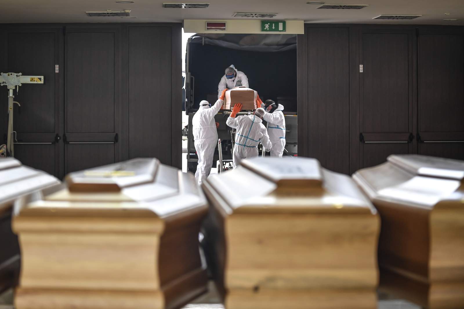Coffins arriving from the Bergamo area, where the coronavirus infections caused many victims, are being unloaded from a military truck that transported them in the cemetery of Cinisello Balsamo, near Milan in Northern Italy, Friday, March 27, 2020.  The new coronavirus causes mild or moderate symptoms for most people, but for some, especially older adults and people with existing health problems, it can cause more severe illness or death.  (Claudio Furlan/LaPresse via AP)