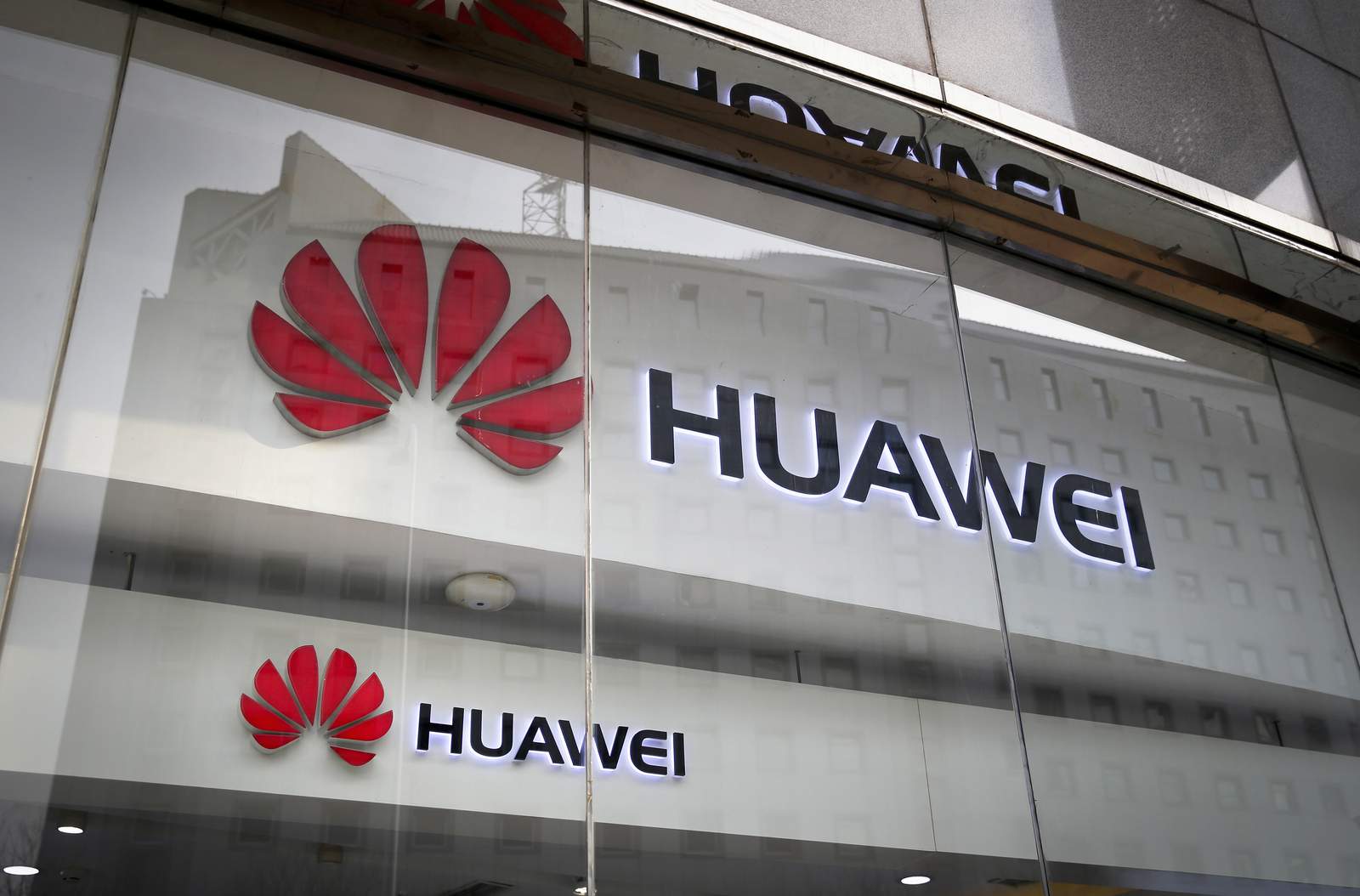 ARCHIVO - En esta foto de archivo del 29 de enero de 2019, los logotipos de Huawei se muestran en el escaparate de su tienda minorista con el reflejo de la oficina del Ministerio de Relaciones Exteriores en Beijing.  Un comité de legisladores insta el jueves 8 de octubre de 2020 al gobierno británico a considerar prohibir al gigante tecnológico chino Huawei de las redes de telefonía móvil de próxima generación del país dos años antes de lo planeado.  (Foto AP / Andy Wong, archivo)