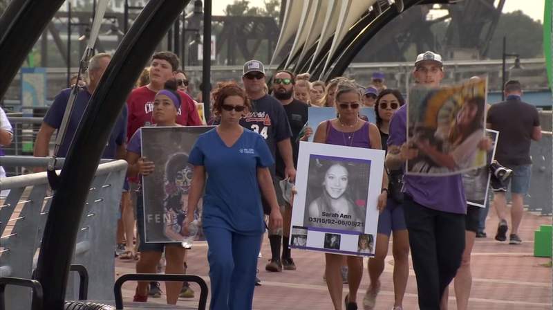 Families hold shoes belonging to loved ones in walk to raise overdose awareness
