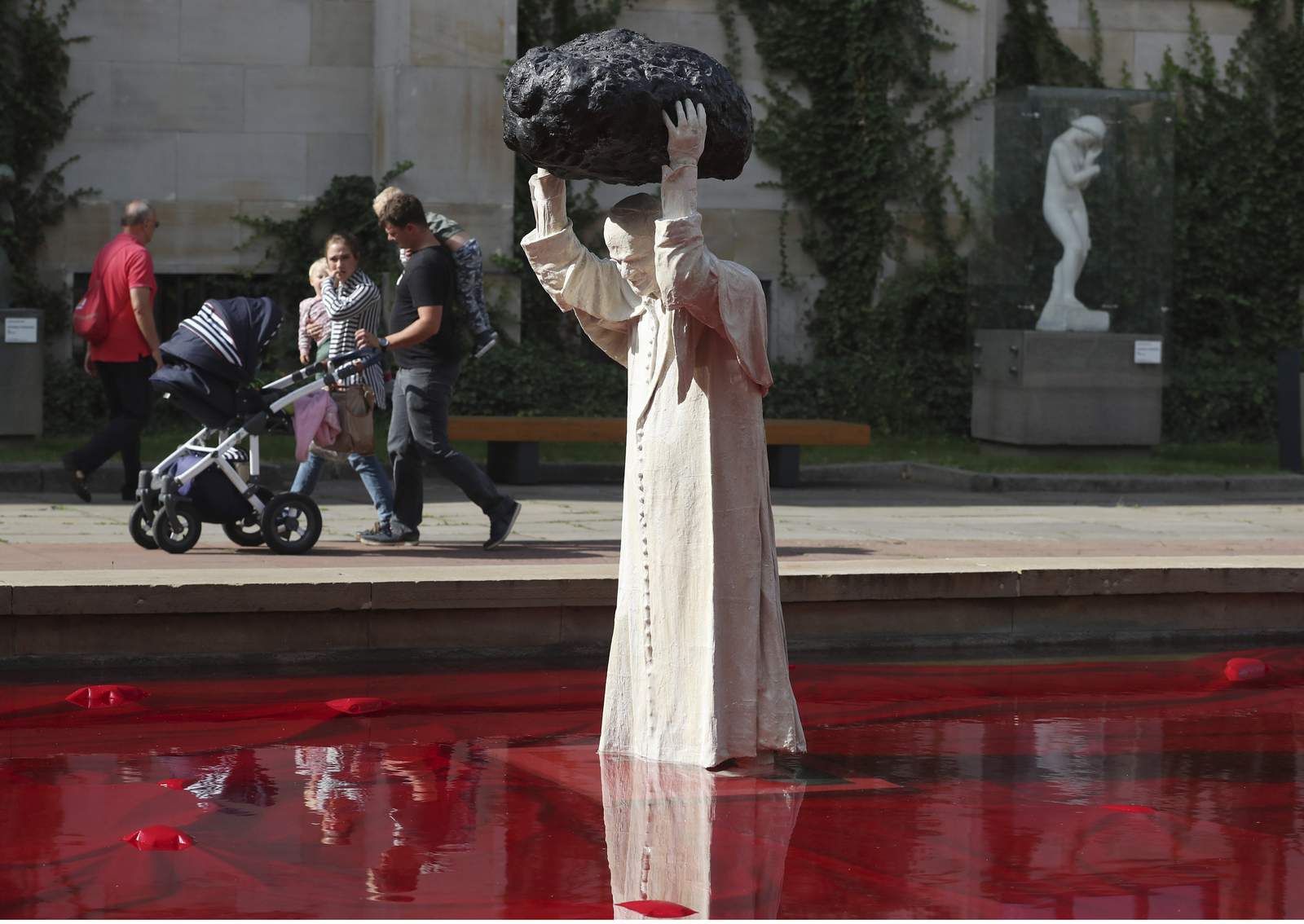 Sculpture of John Paul II with rock, red water makes waves